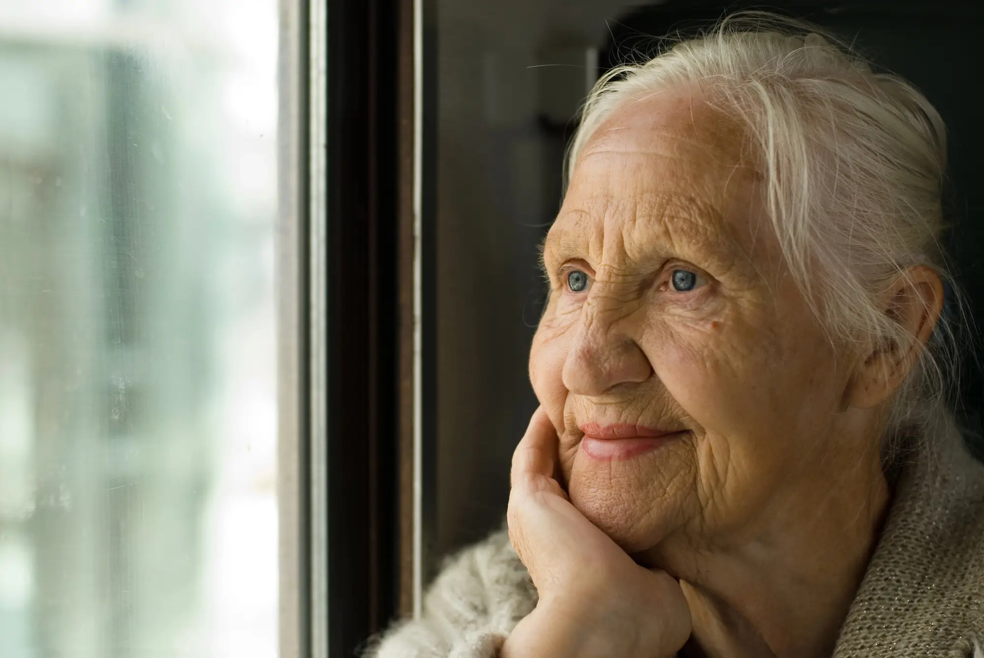 Ältere Dame schaut aus dem Fenster. Demenzbegleitung Life Angel